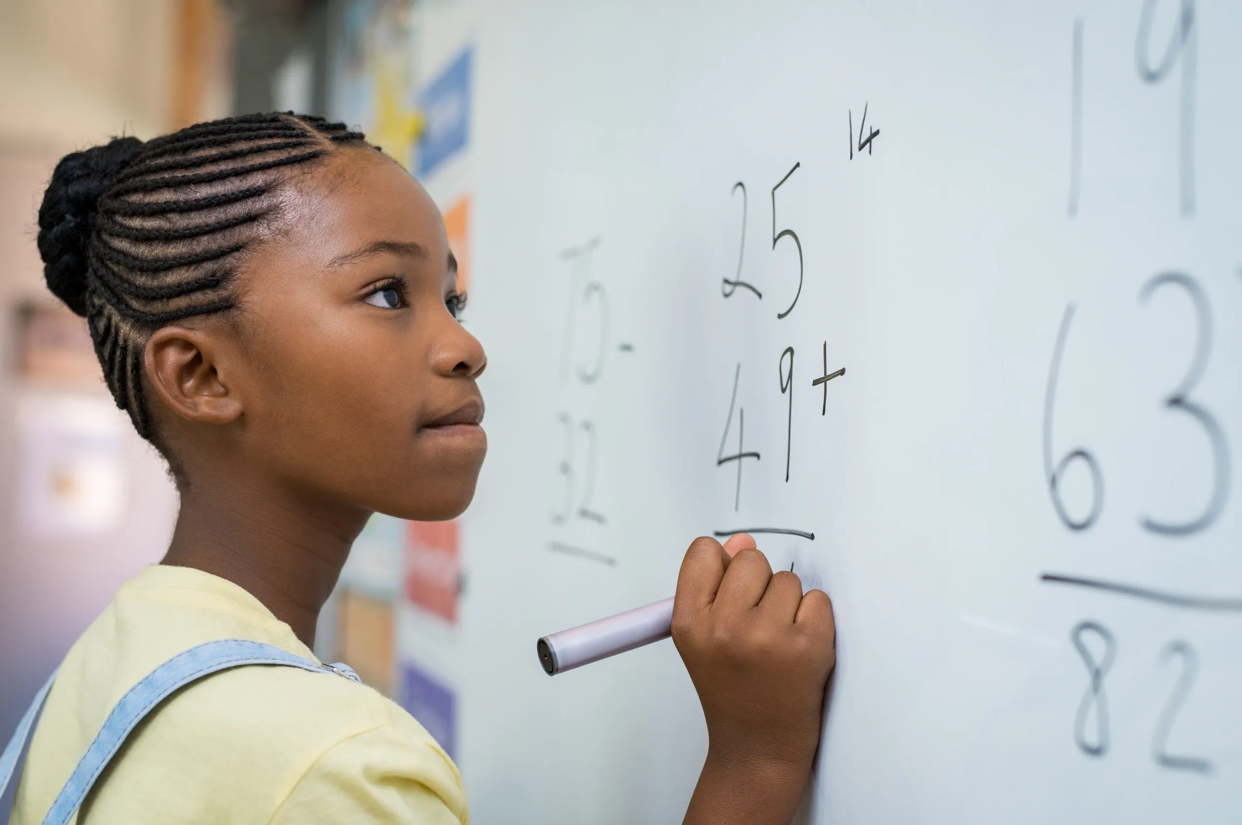 Young student writing mathematics on a classroom board